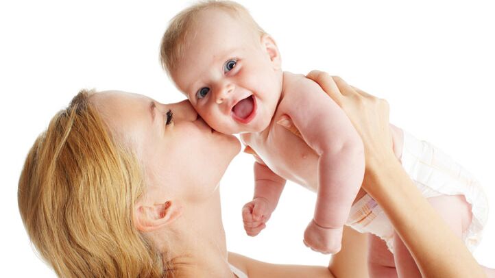 Eine Mutter hält ihr lachendes Baby hoch und gibt ihm einen Kuss auf die Wange.